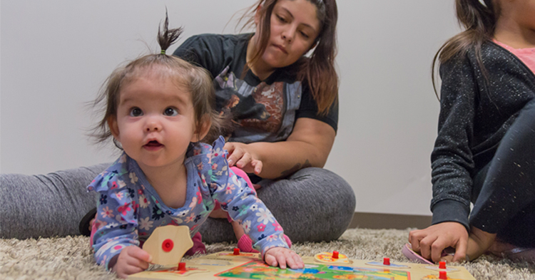 baby girl playing with puzzle together with mom and sister