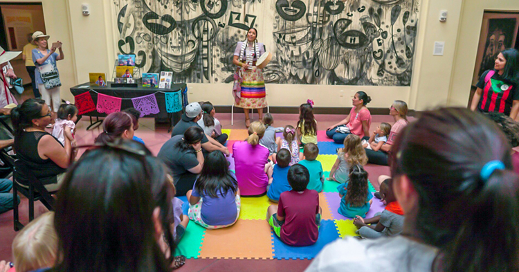 Violet Duncan storytelling with a group of young children.