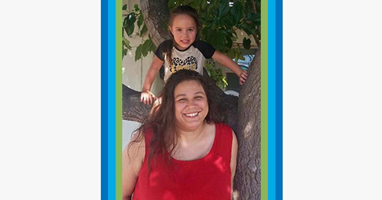 mom and daughter smiling in front of a tree