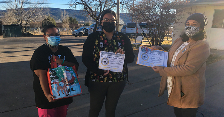 staff from Our Children Shelter stand outside holding a giftbag and award