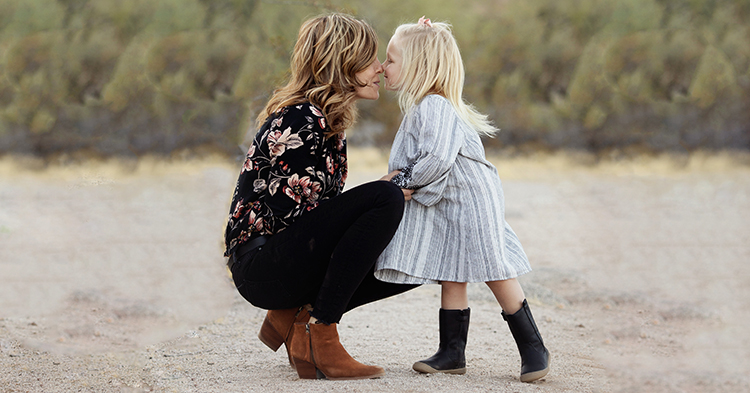 Mom squatting down to embrace daughter at eye-level