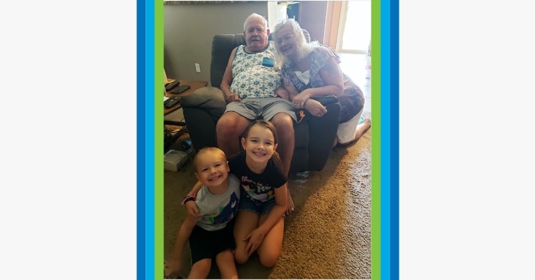 Grandparents smiling on the sofa with their grandchildren