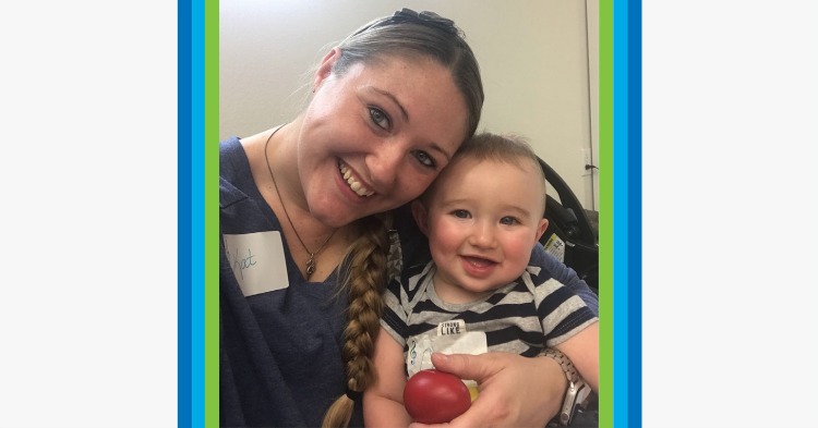 Mom smiling and holding her young son who is wearing a striped shirt