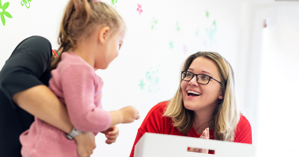 little girl standing with woman in glasses looking at her