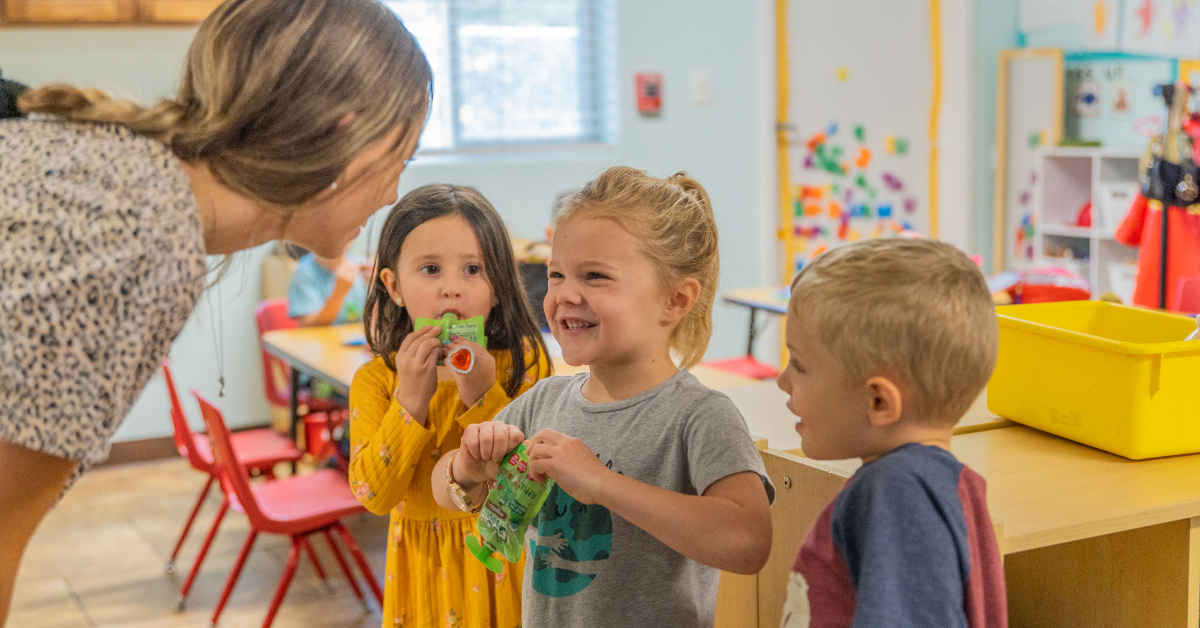 Quality First Arizona preschool in Flagstaff, teacher bending down to interact with students