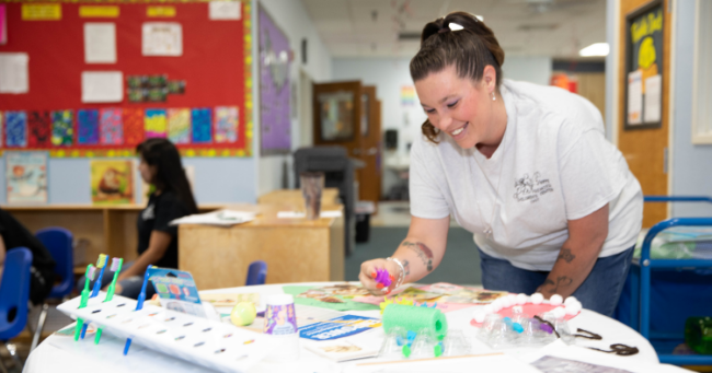 child care teacher smiling at small table with art supplies, Quality First coaching